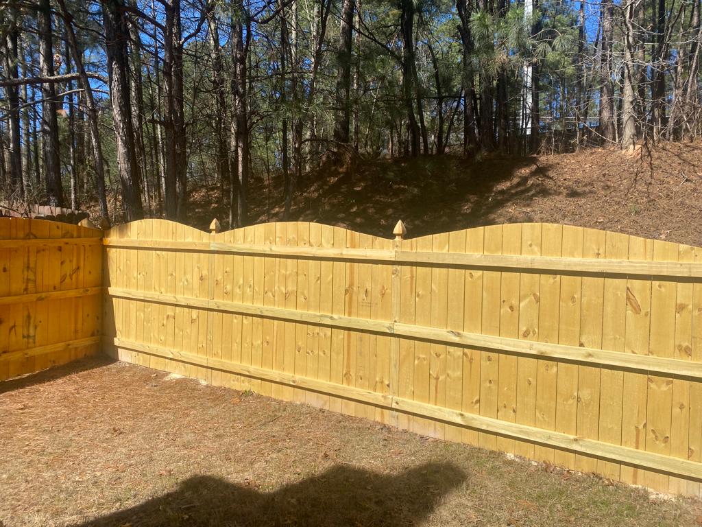 Technician repairing a wooden fence panel in Raleigh backyard