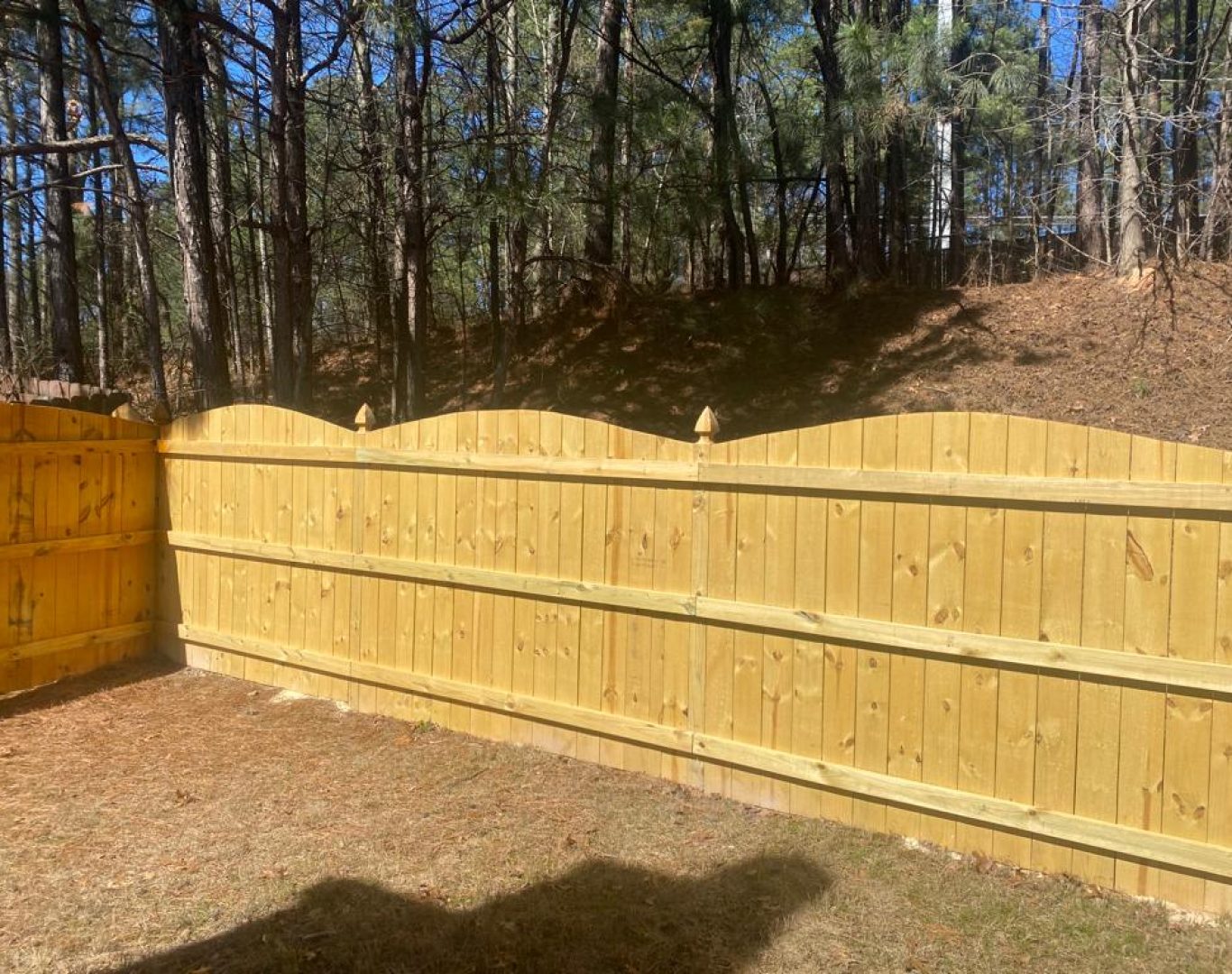 Technician repairing a wooden fence panel in Raleigh backyard